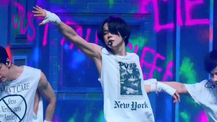 yeonjun during a concert. he has one arm raised.